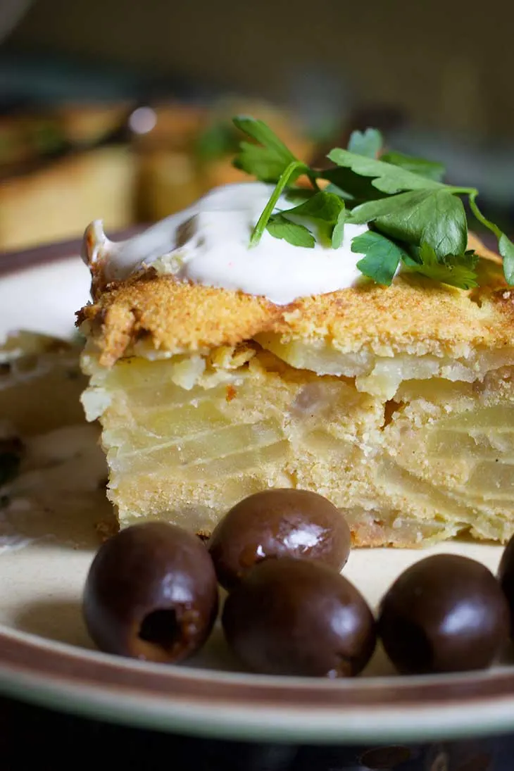 Vegan Potato Tortilla layered on a plate with olives