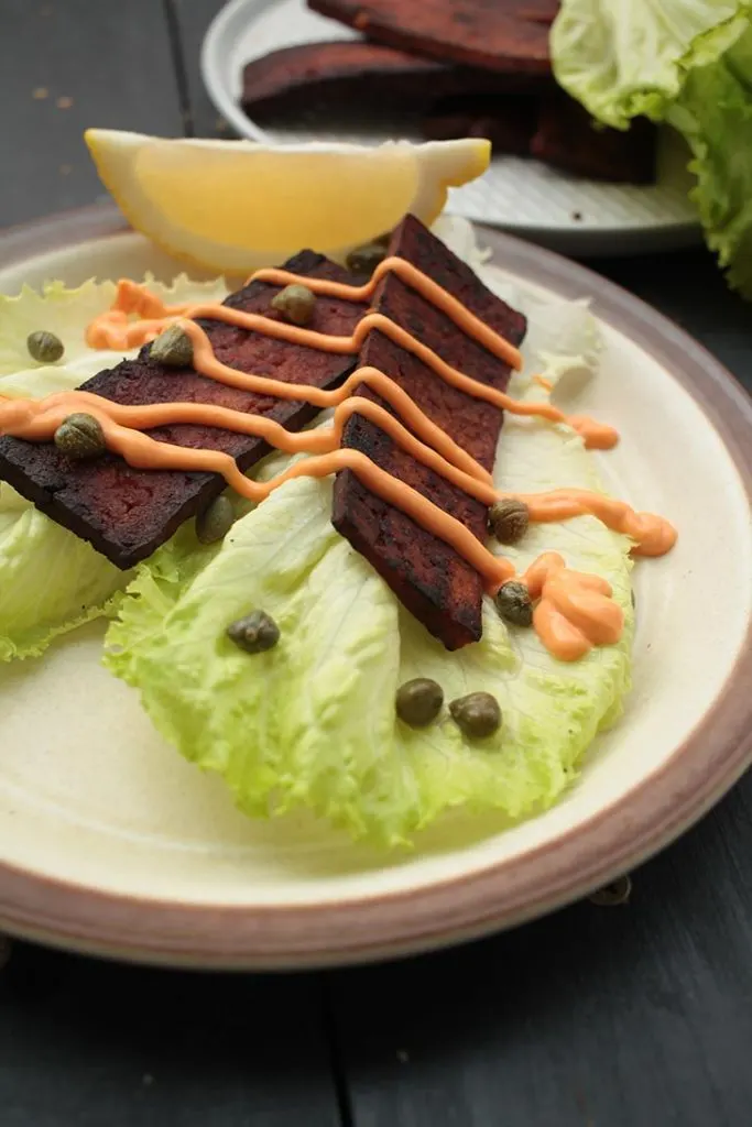 vegan tofu bacon on lettuce with sauce