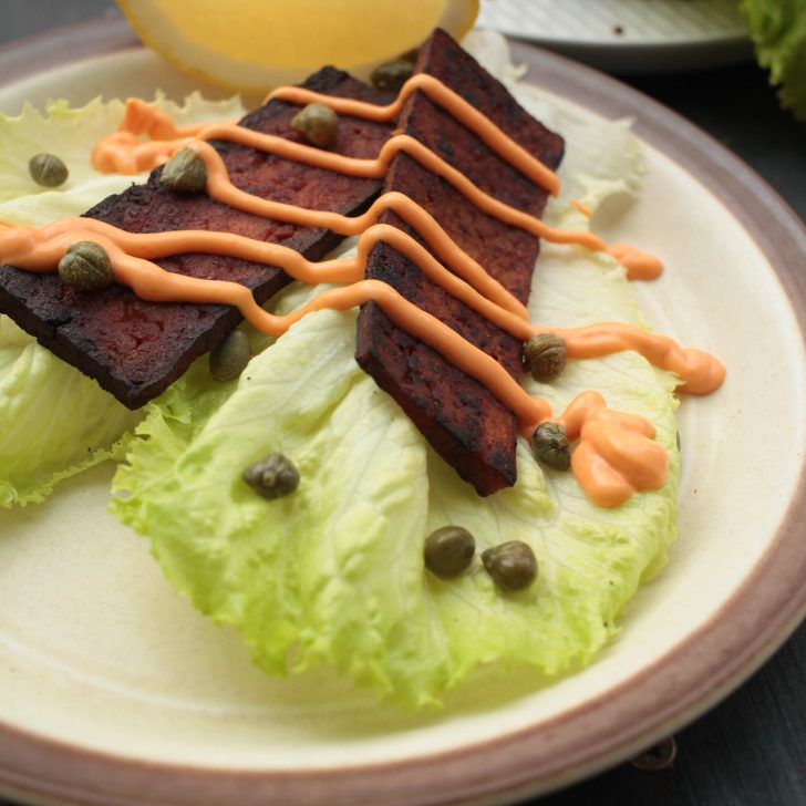 vegan tofu bacon on lettuce with sauce