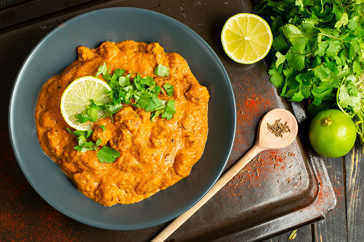 vegan butter chicken in a grey plate on a dark countertop with wooden spoon