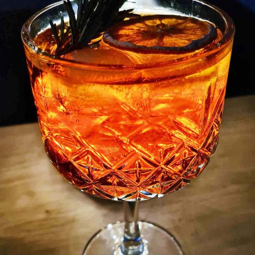 Aperol tonic cocktail with ice and an orange slice in a wine glass