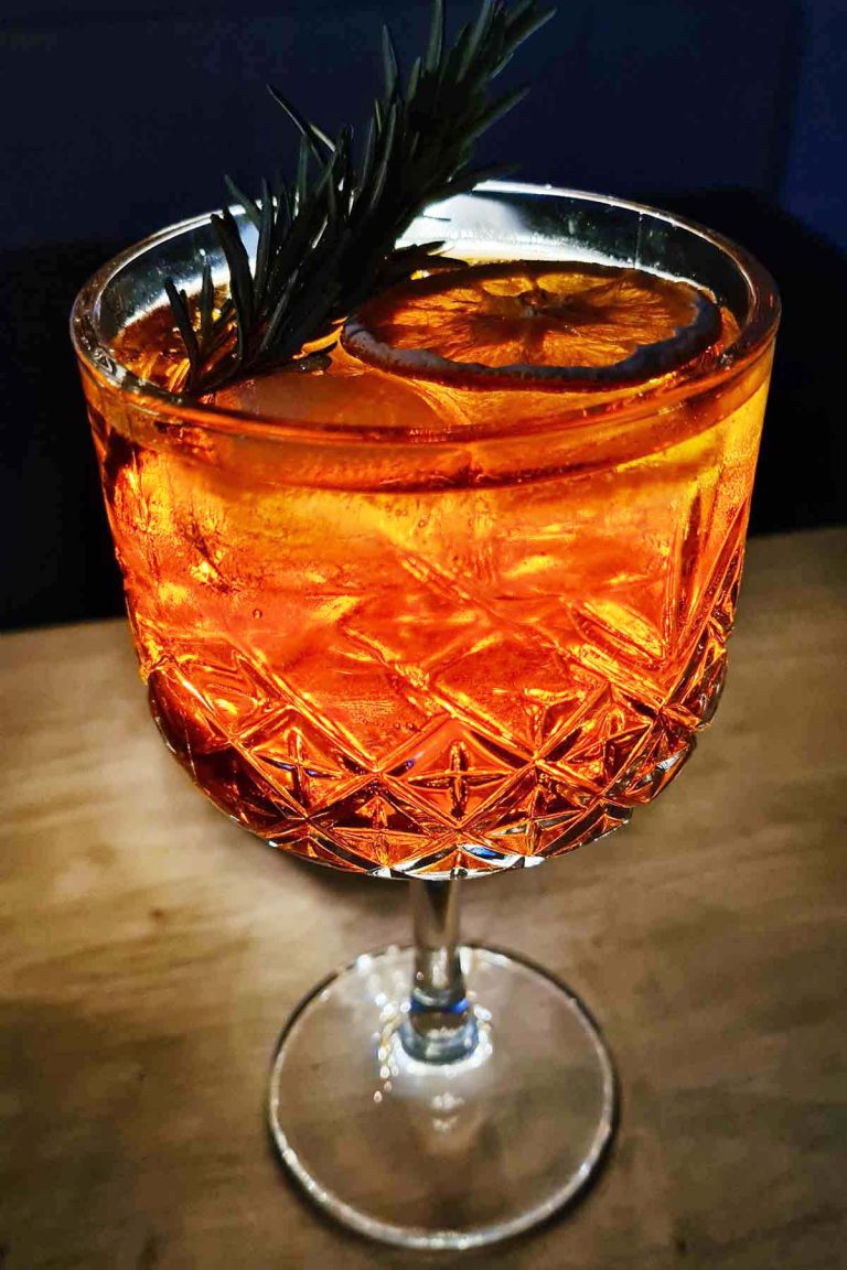 Aperol tonic cocktail with ice and an orange slice in a wine glass