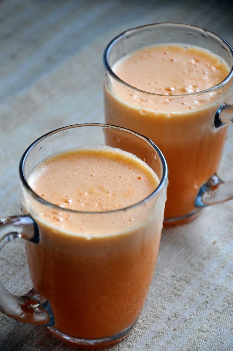 Two glass mugs of fresh frothy apricot juice