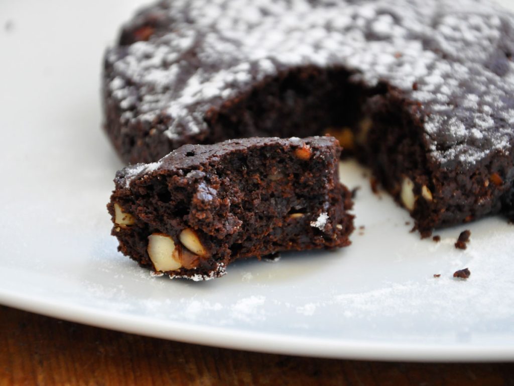 Slice of moist vegan chocolate cake with walnuts and rum raisins