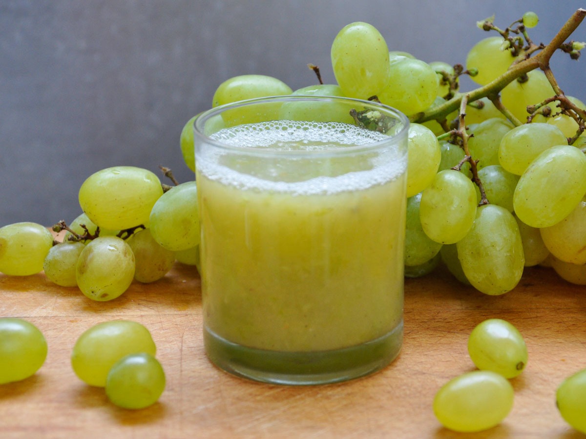 Fresh cucumber and green grapes beside a glass of juice