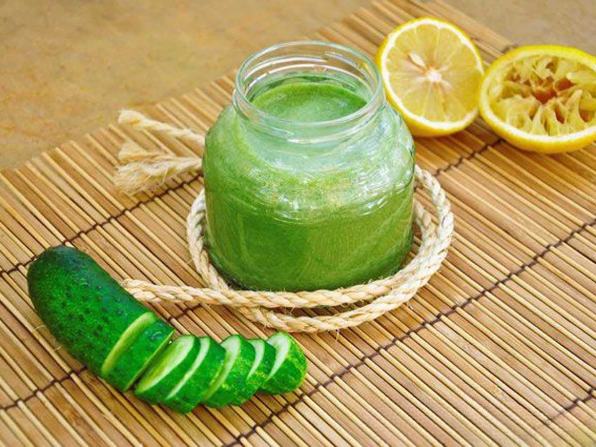 Green juice in a glass jar with sliced cucumber and lemon