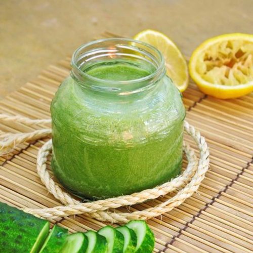 Green juice in a glass jar with sliced cucumber