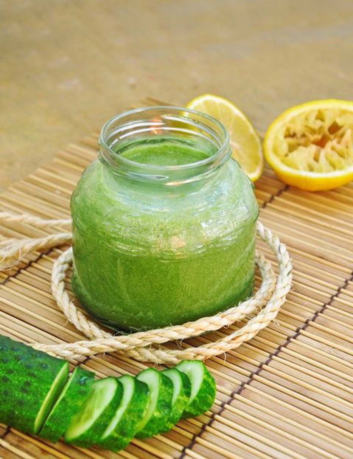 Green juice in a glass jar with sliced cucumber