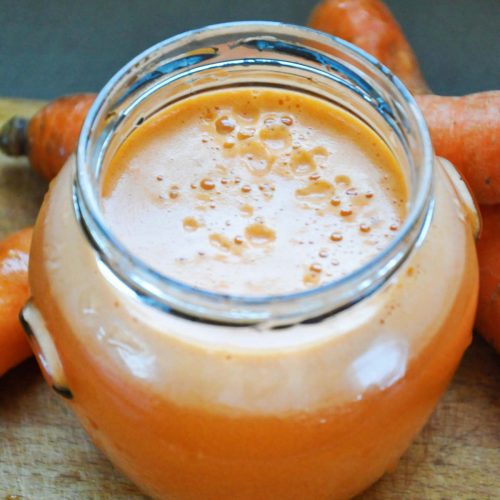 Fresh gingery carrot juice in a glass jar, overhead view