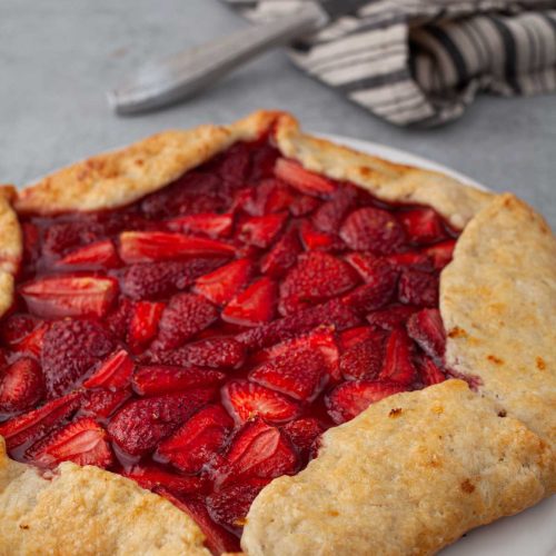 Whole rustic strawberry galette on parchment paper