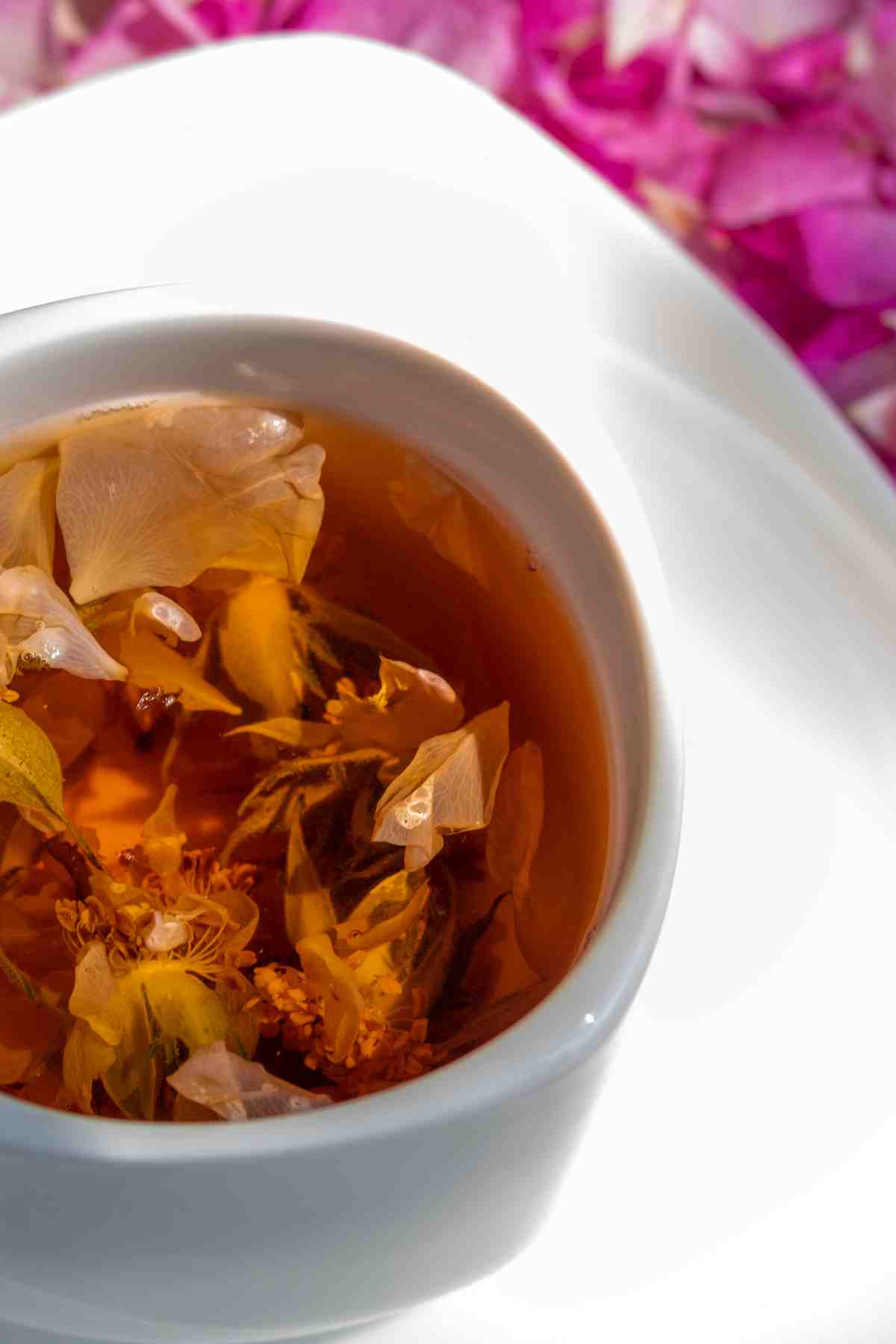 Cup of infused rose petal tea with floating petals