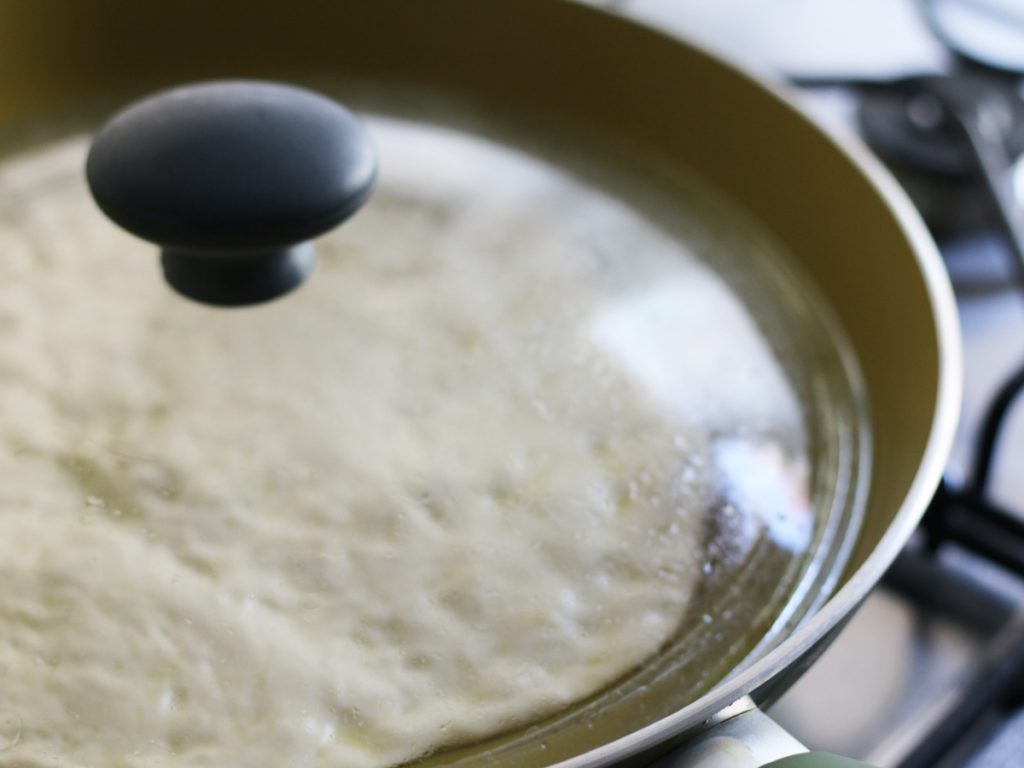A lid placed on a pan of stovetop pizza