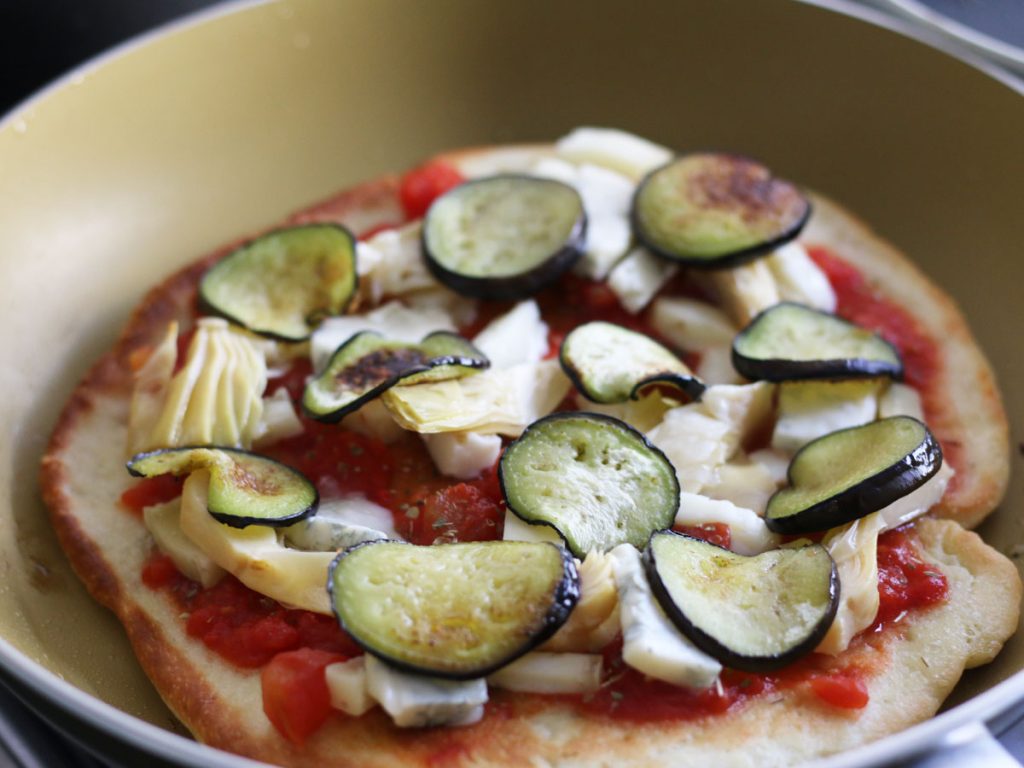Adding mozzarella and eggplant to stovetop pizza