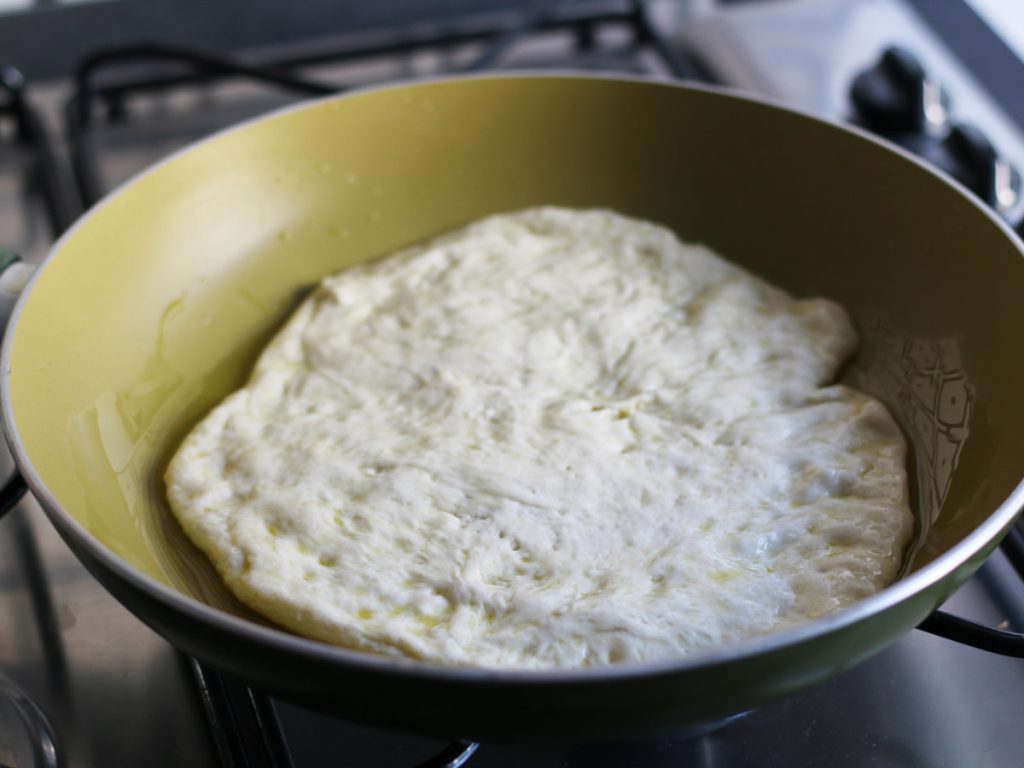 Pizza dough pressed into a pan by hand