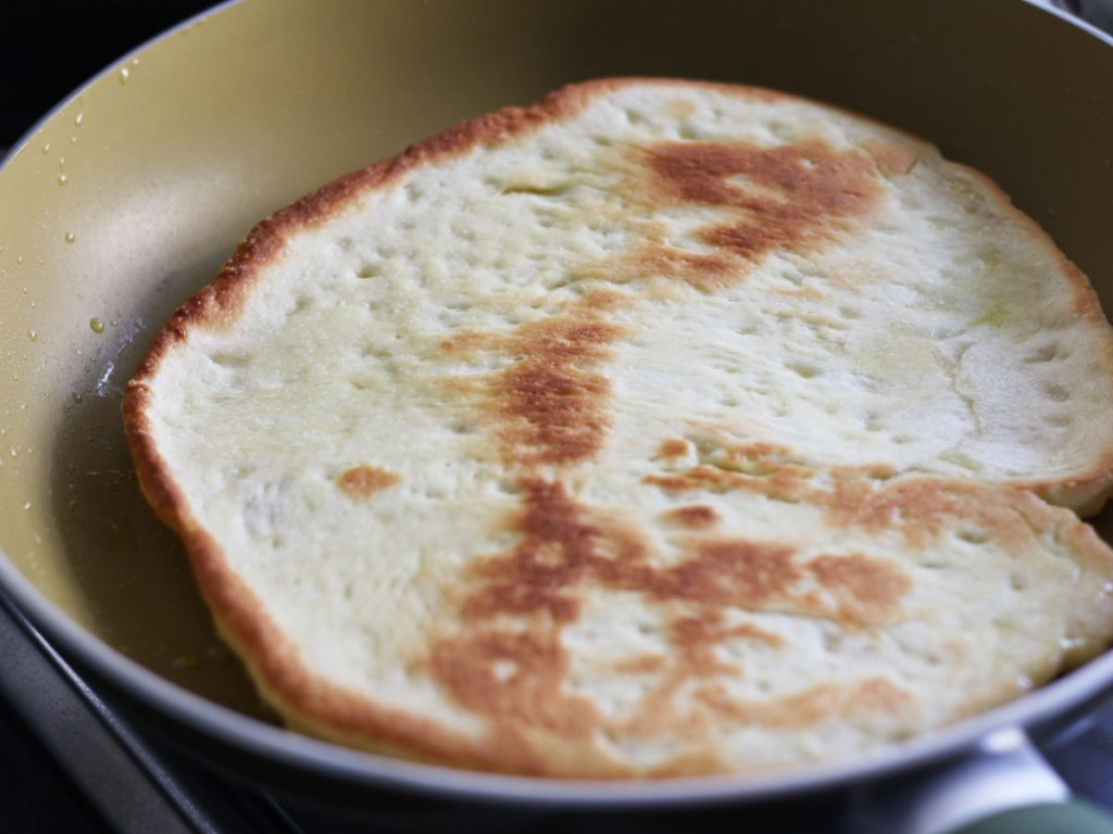 Flipping the stovetop pizza base in the pan