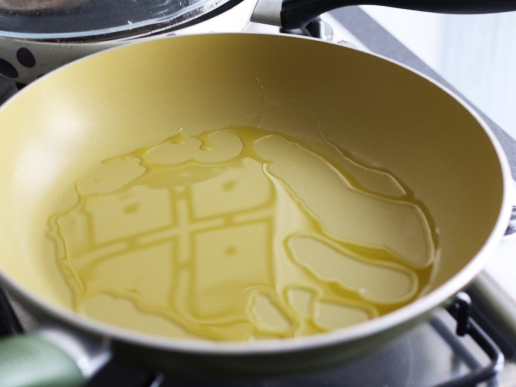 Olive oil heating in a pan for stovetop pizza