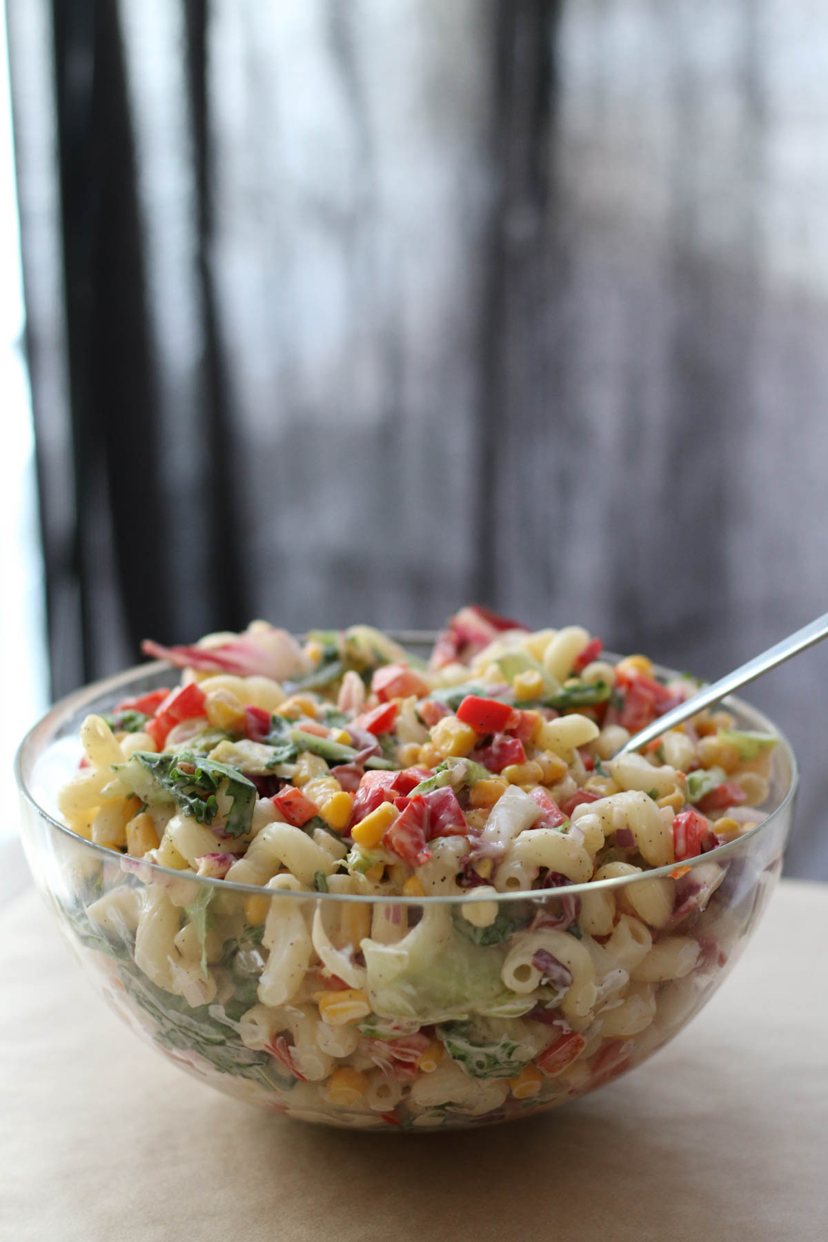 Creamy pasta salad with corn and peppers in a white bowl