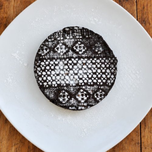 Vegan chocolate cake decorated with a lace powdered-sugar pattern