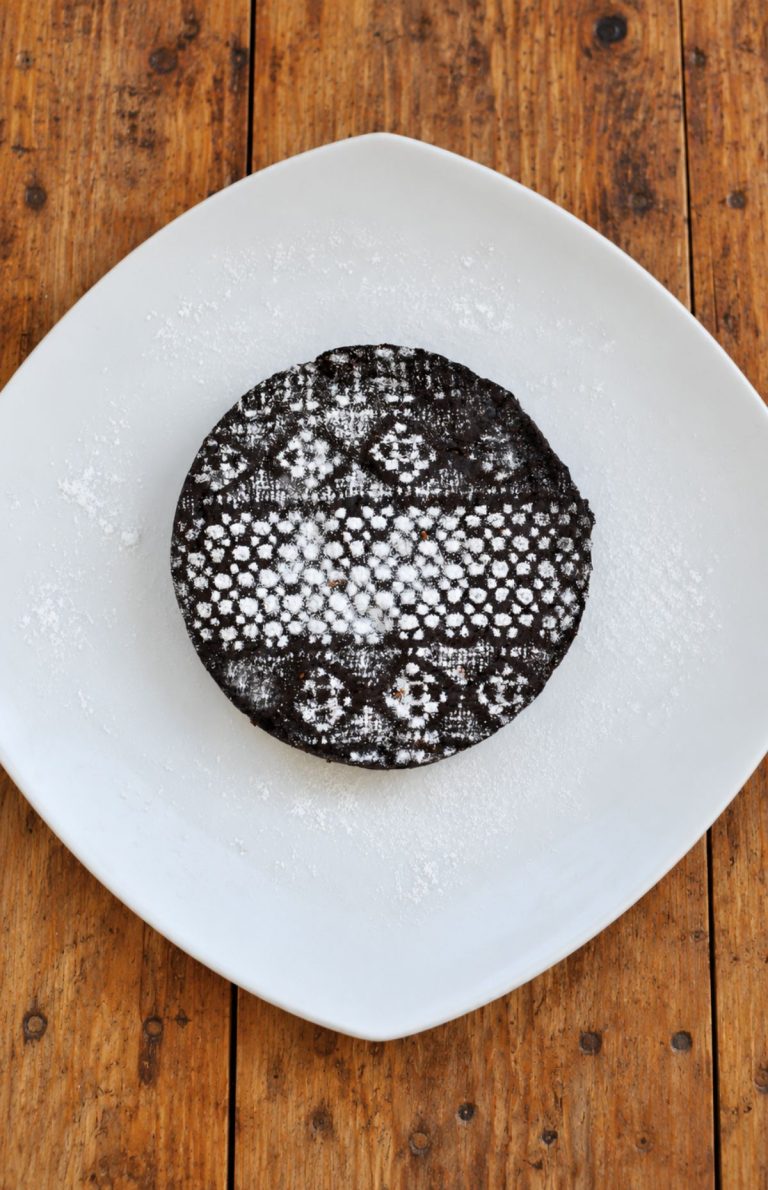 Vegan chocolate cake decorated with a lace powdered-sugar pattern