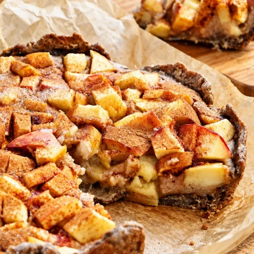 Apple custard tart with a slice cut out, showing the soft vanilla custard under the apples