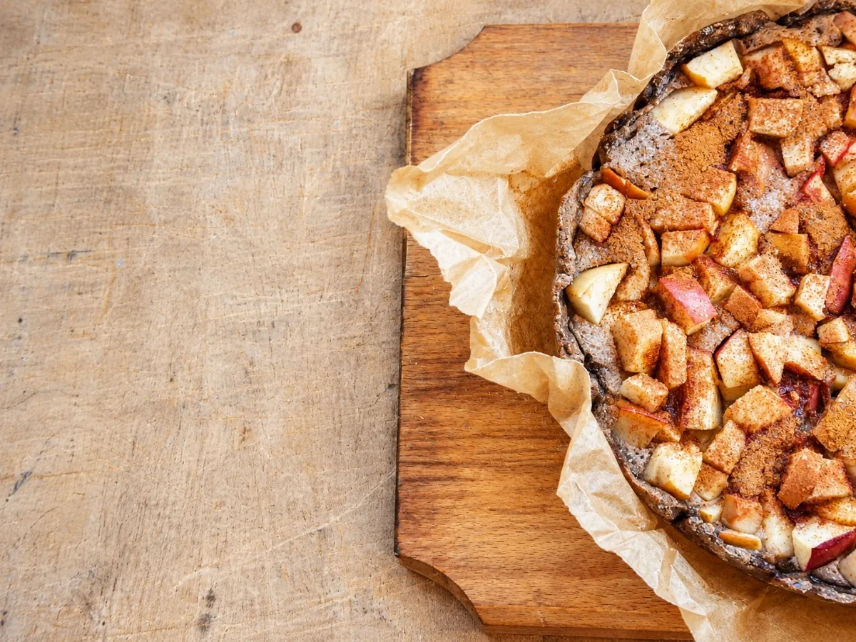 Apple tart with a whole wheat crust on a wooden cutting board, seen from above
