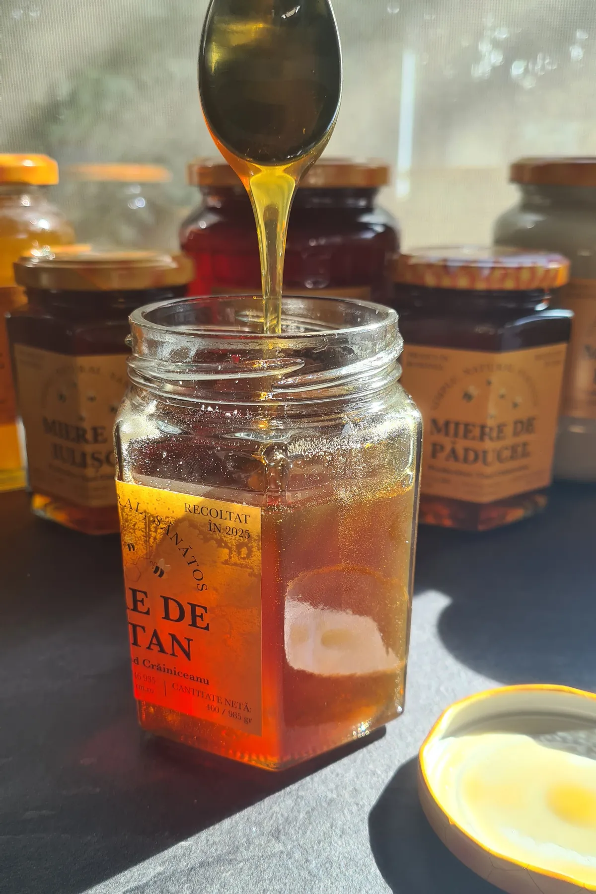 Chestnut honey dripping from a spoon into an open jar