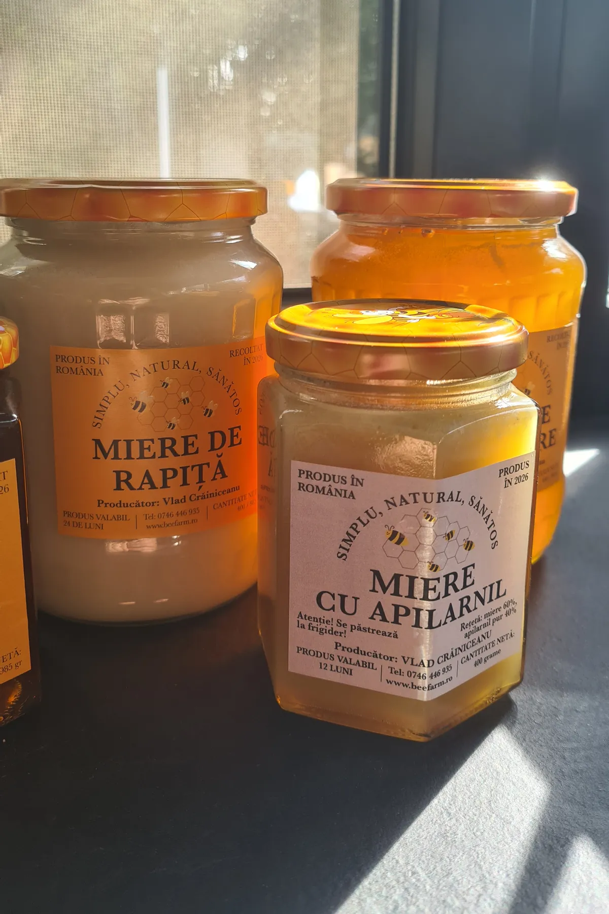 Jar of creamy white rapeseed honey next to a jar of honey with apilarnil